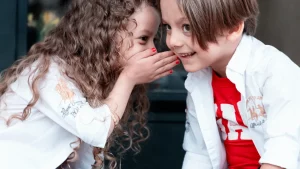 Ein Kind flüstert einem andereen etwas ins Ohr