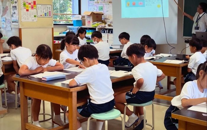 Schulkinder arbeiten in einem japanischen Klassenzimmer konzentriert an Tischen.