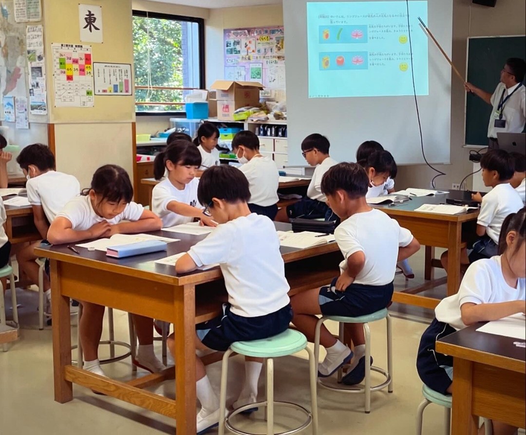 Schulkinder arbeiten in einem japanischen Klassenzimmer konzentriert an Tischen.
